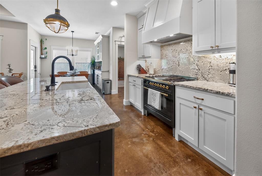 6371 Mill Run Road Athens, TX 75751 - Photo 5 of 40 The kitchen features an island with a light-colored granite countertop and sink, a black faucet, and white cabinetry