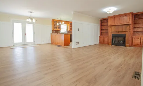 an empty room with wooden floor fireplace and windows