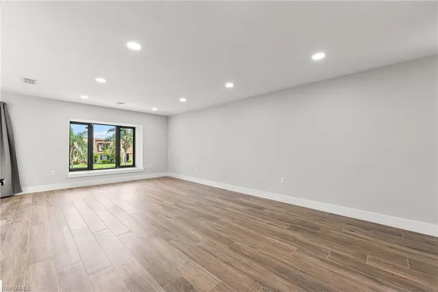 a view of kitchen with kitchen island wooden floor granite top appliances and cabinets