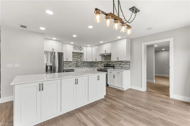 a kitchen with stainless steel appliances kitchen island granite countertop a refrigerator and a stove top oven