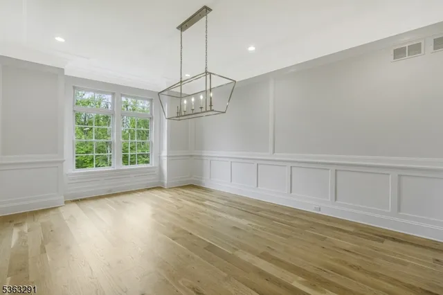 an empty room with wooden floor a fireplace and windows