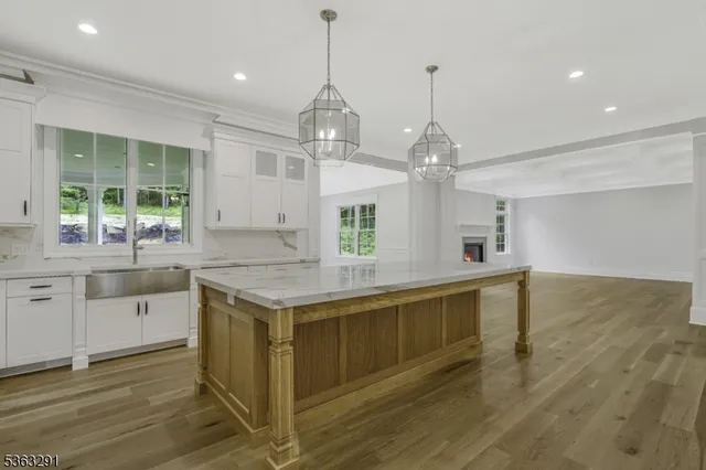 a view of a livingroom with a fireplace a ceiling fan and wooden floor