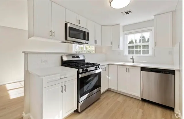 a kitchen with white cabinets stainless steel appliances and sink