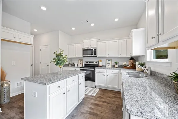 a kitchen with granite countertop a sink and white cabinets