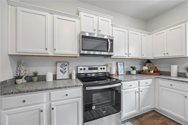 a kitchen with granite countertop white cabinets sink and stainless steel appliances