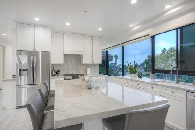 a large kitchen with kitchen island a large window cabinets a sink and stainless steel appliances