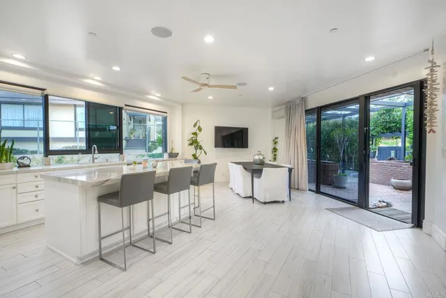 a open kitchen with stainless steel appliances kitchen island granite countertop a refrigerator a stove a dining table and chairs with wooden floor