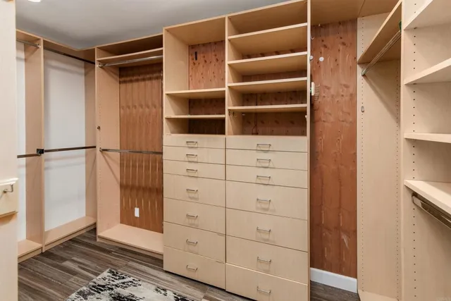 a view of an empty room with wooden floor and a ceiling fan