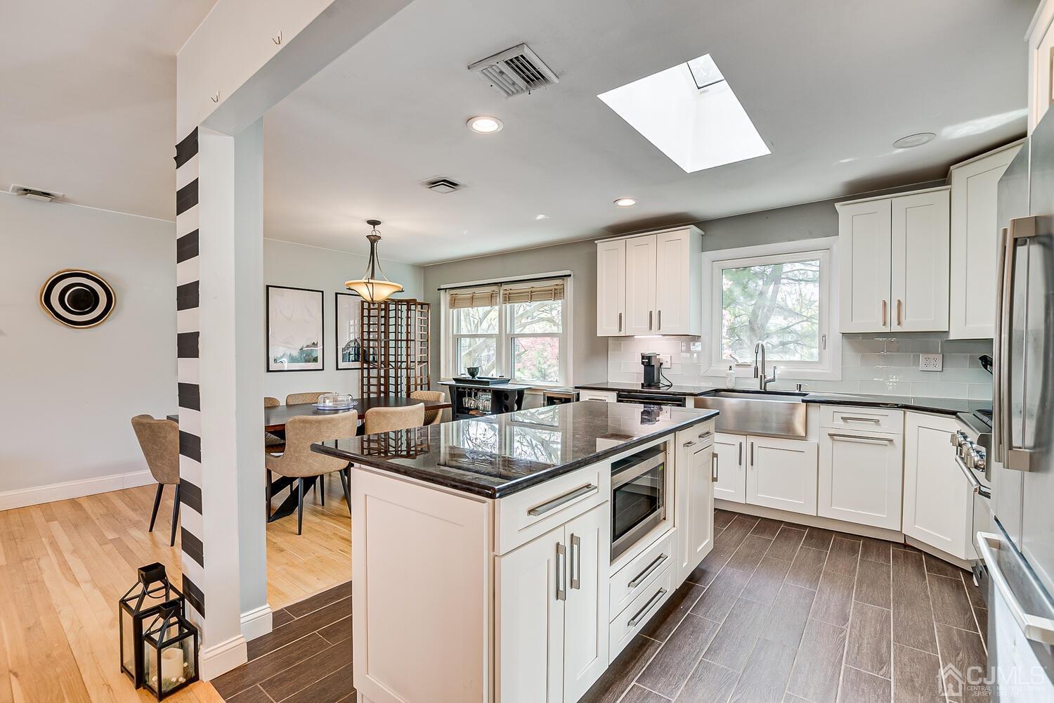 20 Homestead Road Metuchen, NJ 08840 - Photo 20 of 49 a kitchen with stainless steel appliances granite countertop a stove a sink dishwasher a microwave oven and a dining table with wooden floor
