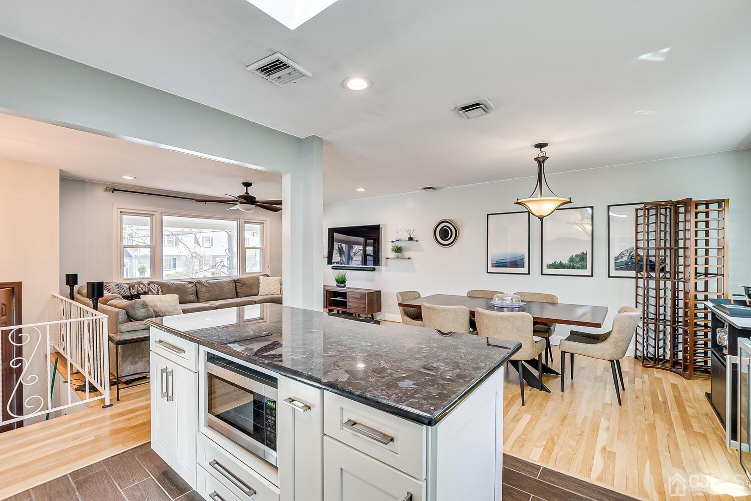 20 Homestead Road Metuchen, NJ 08840 - Photo 22 of 49 a kitchen with granite countertop a stove a sink a dining table and chairs with wooden floor