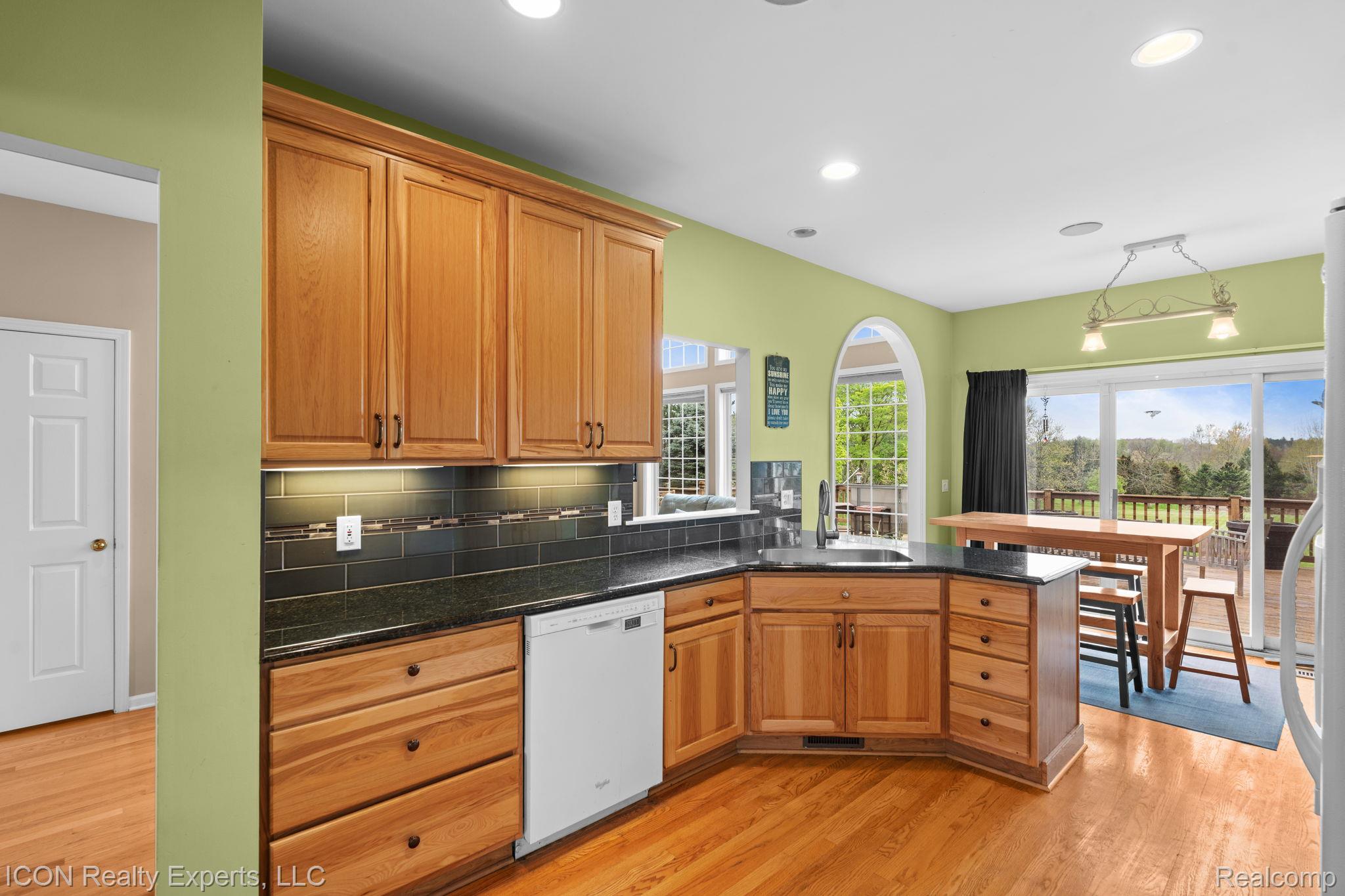 5128 Baldwin Road Metamora, MI 48455 - Photo 25 of 68 Kitchen featuring a peninsula, light wood-style floors, white dishwasher, dark stone countertops, and wood finish cabinets
