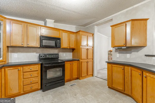 a kitchen with stainless steel appliances granite countertop a stove a sink and a refrigerator with wooden cabinets