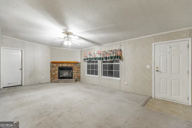an empty room with windows fireplace and a ceiling fan
