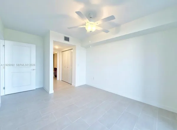 an empty room with closet and a chandelier fan