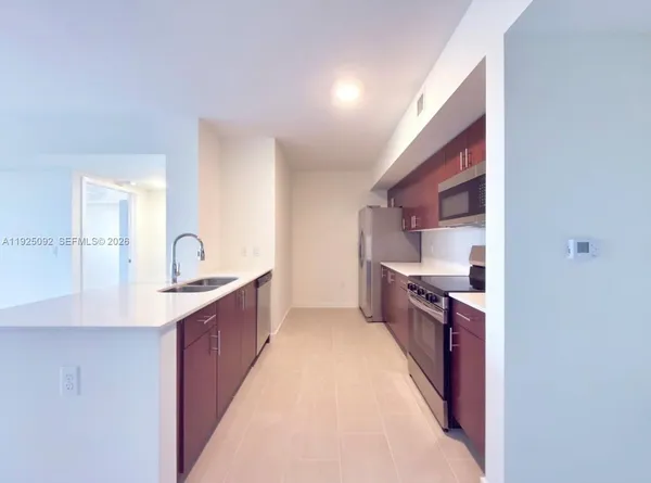 a large kitchen with stainless steel appliances a sink and cabinets