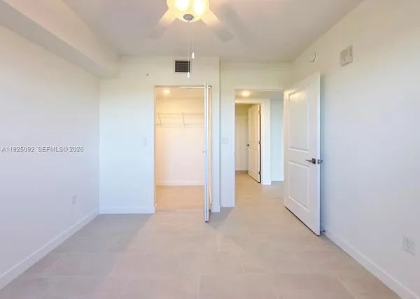 an empty room with kitchen view and natural light