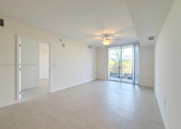 an empty room with windows and chandelier fan