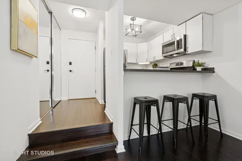 a kitchen with stainless steel appliances a table chairs in it and wooden floors