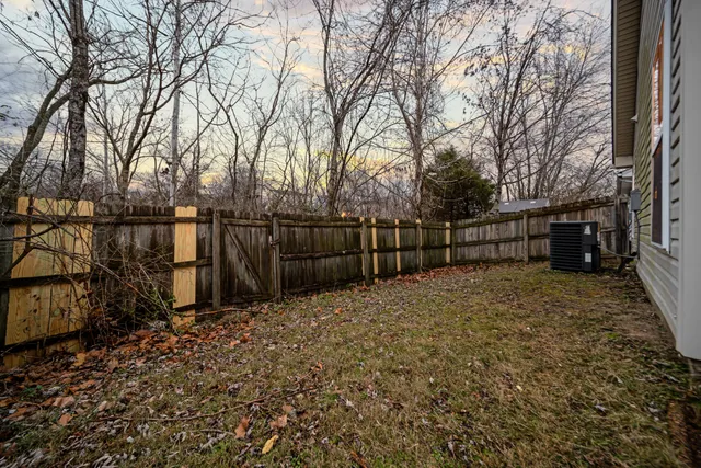a view of backyard with wooden fence and large trees