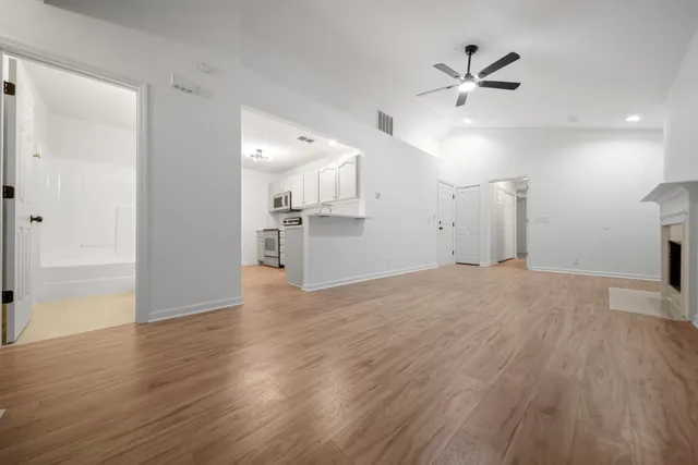 a view of empty room with wooden floor and ceiling fan