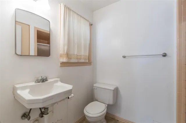 a bathroom with a toilet a sink and mirror