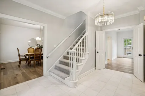 a dining room with wooden floor a chandelier a wooden table and chairs