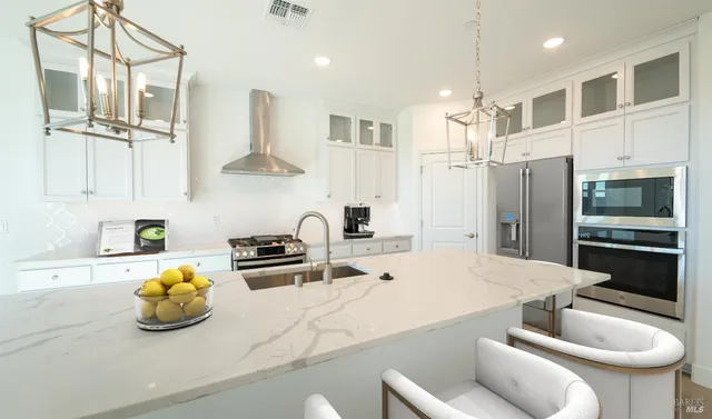 a kitchen with stainless steel appliances kitchen island granite countertop a sink and a refrigerator