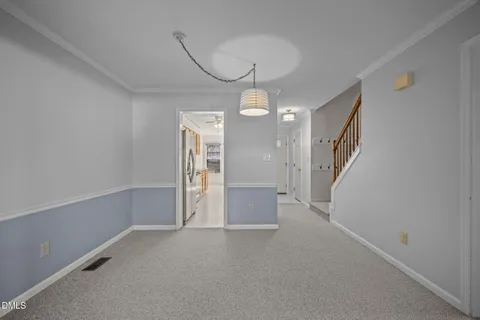 a view of an empty room with chandelier fan and a window