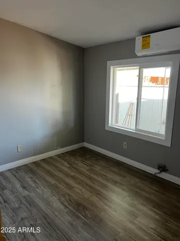 a view of empty room with wooden floor and window