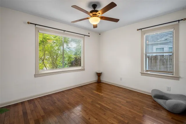 a view of an empty room with window and wooden floor