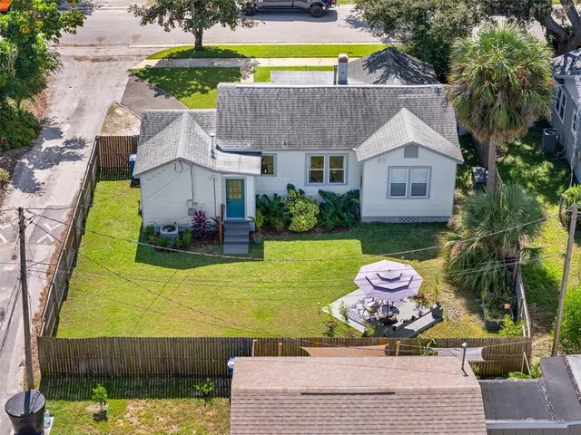 an aerial view of a house with swimming pool and large trees