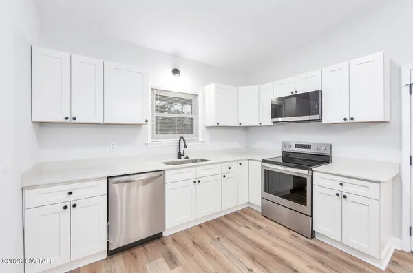 a kitchen with cabinets stainless steel appliances a sink and a stove