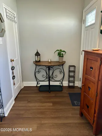 a view of a hallway to room with wooden floor and window