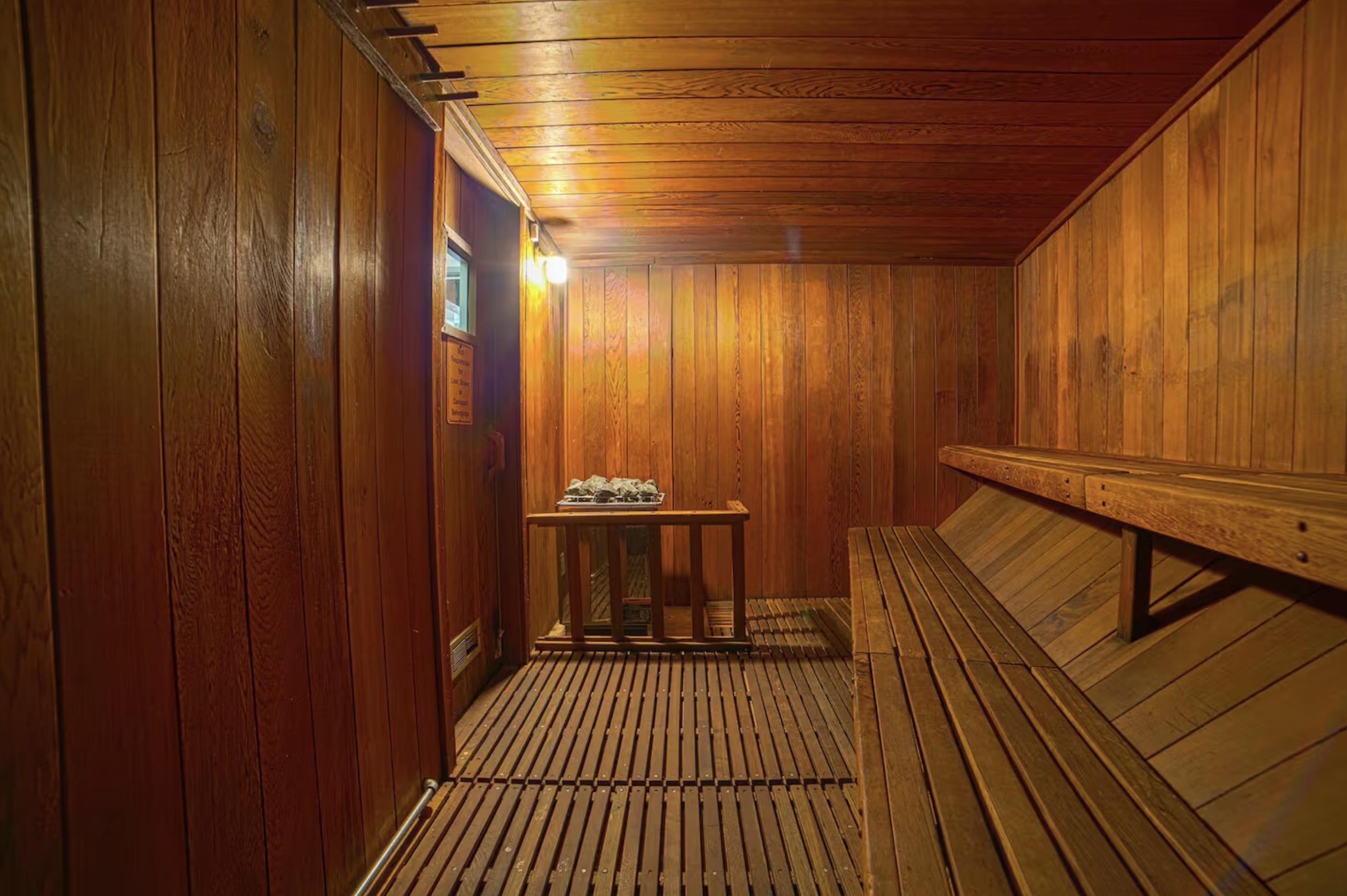 153 Lake Mary Road, Unit 114 Mammoth Lakes, CA 93546 - Photo 22 of 22 Dedicated sauna room featuring extensive wood paneling, slatted wood flooring, built-in tiered wood benches, and a central sauna heater with protective railing