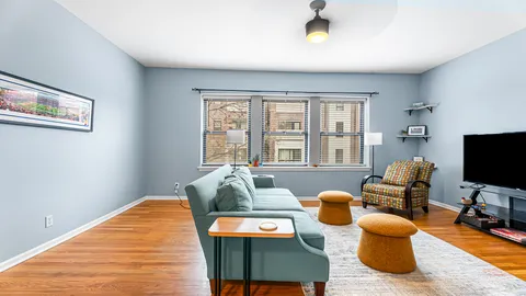a living room with furniture a flat screen tv and a floor to ceiling window
