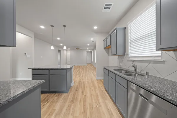 a large kitchen with granite countertop a sink a counter space appliances and cabinets