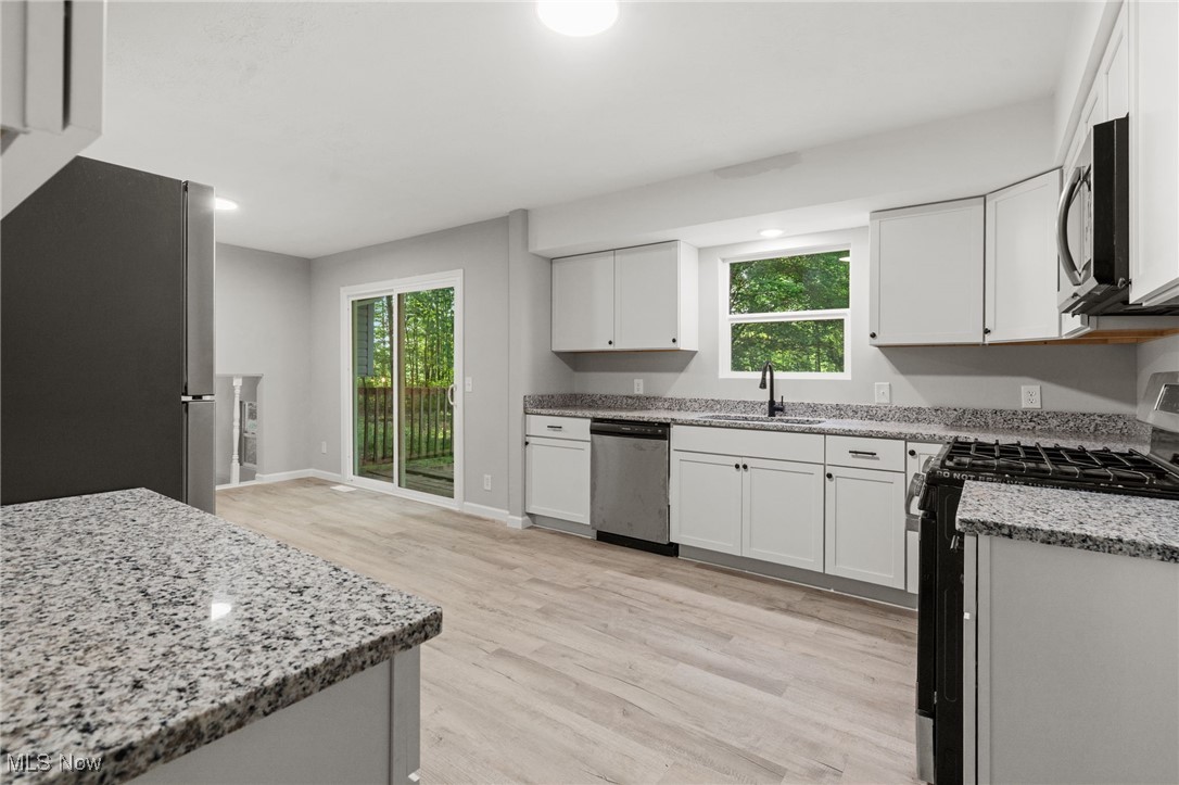 4232 Wilson Avenue Ravenna, OH 44266 - Photo 11 of 28 Kitchen featuring stainless steel appliances, light wood-style floors, light stone counters, and plenty of natural light