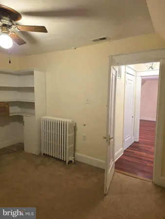 a view of an empty room with wooden floor and a fireplace