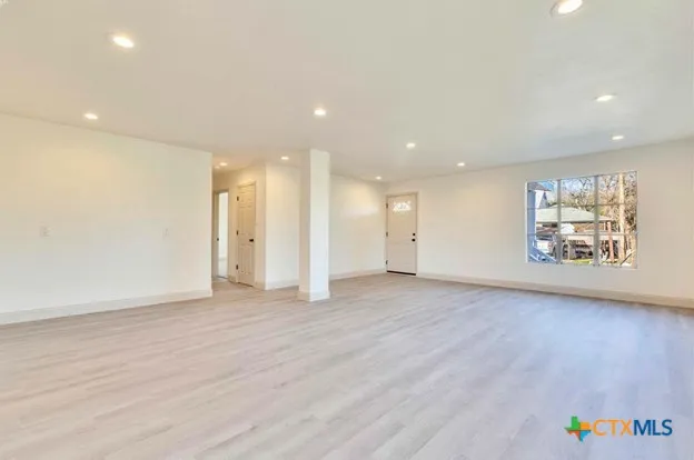 a view of an empty room with a window and wooden floor