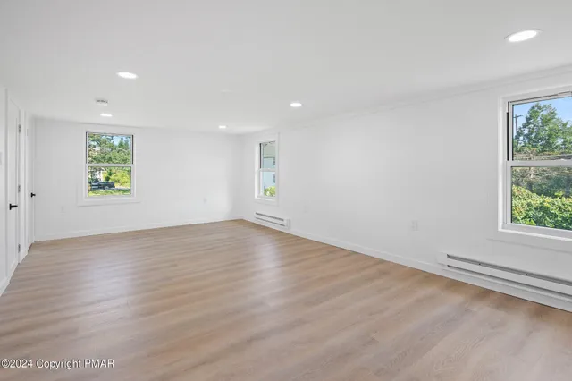 an empty room with wooden floor and windows
