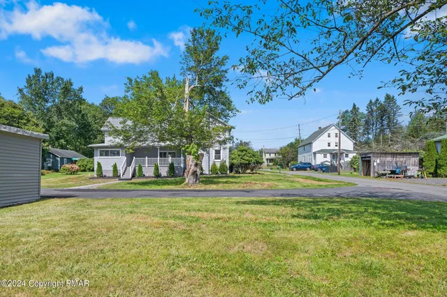 a front view of house with yard and trees in the background