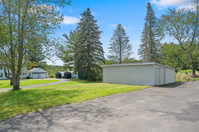 a view of a house with yard and trees in the background