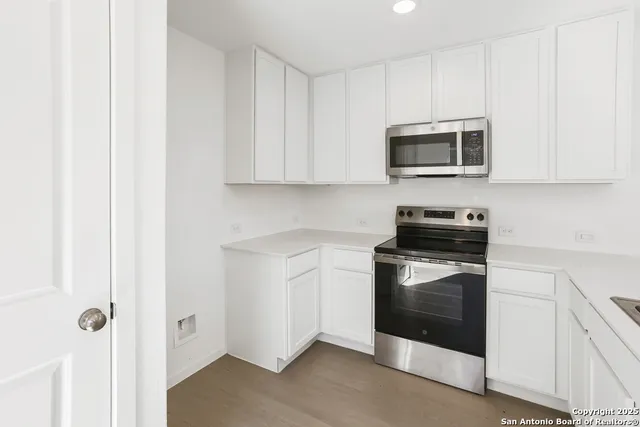 a kitchen with stainless steel appliances granite countertop white cabinets a microwave a sink and a refrigerator