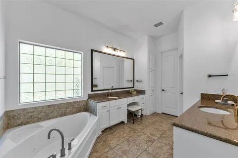 a bathroom with a granite countertop tub sink and mirror