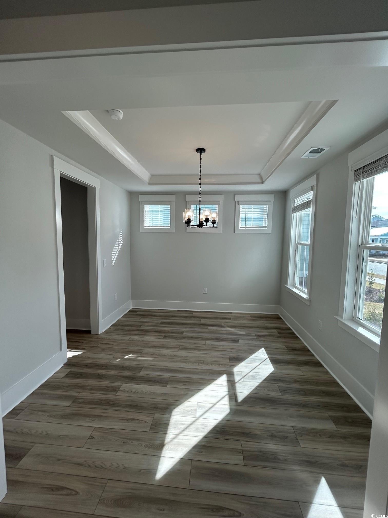 622 Braselton Lane Myrtle Beach, SC 29588 - Photo 3 of 15 Unfurnished dining area with a tray ceiling, a notable chandelier, visible vents, wood finished floors, and baseboards