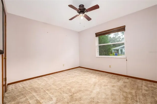 an empty room with a window and a ceiling fan