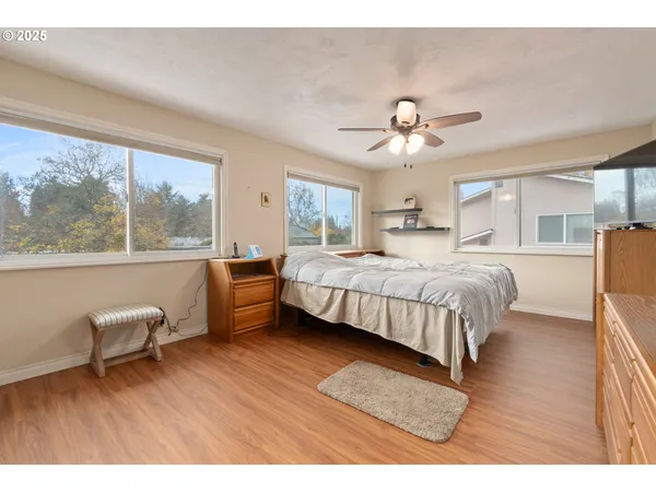 a bedroom with a bed wooden floor and a large window