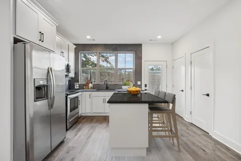 a kitchen with a refrigerator a sink and white cabinets