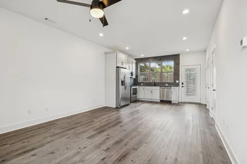 an empty room with wooden floor fan and windows