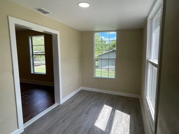 an empty room with wooden floor and windows